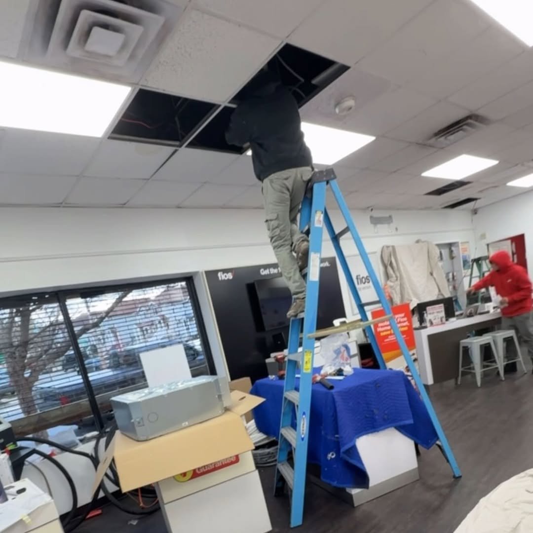 Worker on blue ladder replacing ceiling tiles in an office break room