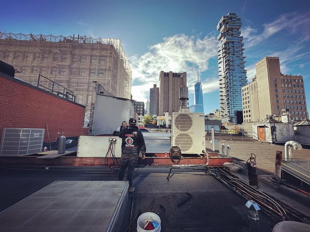 View from rooftop of city skyline with buildings, construction equipment, and blue sky with clouds