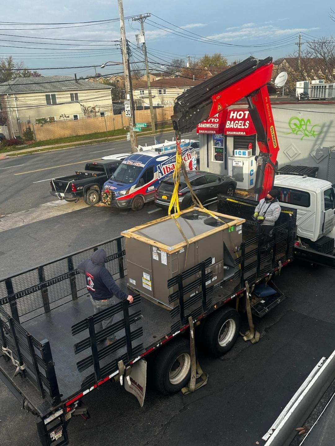 Aerial view of a red and black mobile bagel shop with hydraulic lift next to other food trucks in a parking lot