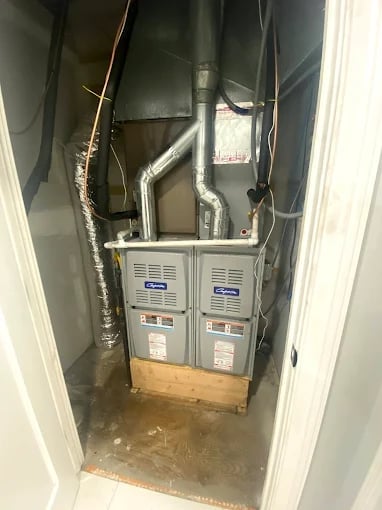 Indoor HVAC furnace unit with metal ductwork and wiring in a utility closet