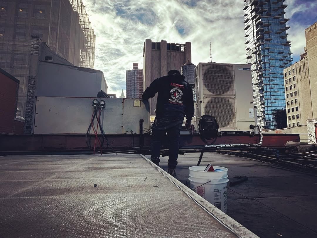 Person in dark clothing skateboarding on rooftop with urban skyline and air conditioning units in background